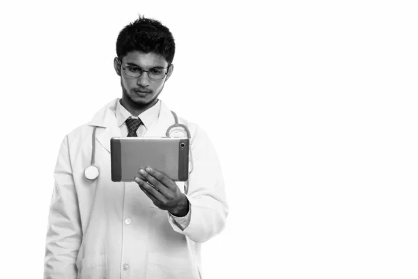 Studio shot of young handsome Indian man doctor holding digital tablet — Stock Photo, Image