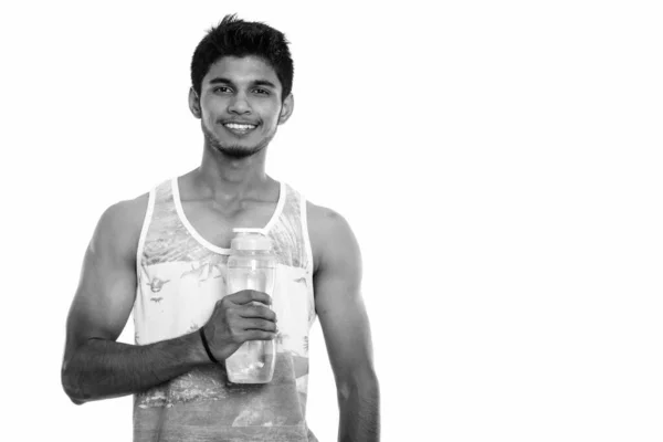 スタジオショットの若いです幸せなインド人男性笑顔ながら保持水ボトル — ストック写真
