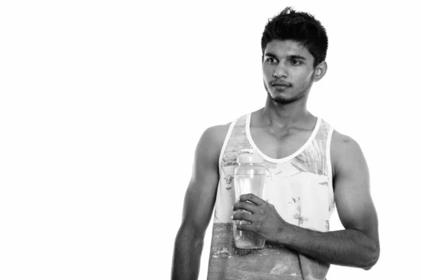 Stúdió lövés fiatal jóképű indiai férfi kezében vizes palack és gondolkodás — Stock Fotó
