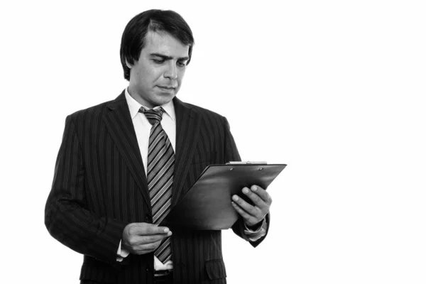 Studioaufnahme eines jungen persischen Geschäftsmannes, der auf Klemmbrett liest — Stockfoto