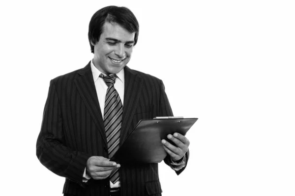 Studio zdjęcie młodego szczęśliwego perskiego biznesmena uśmiechającego się podczas czytania na tablicy — Zdjęcie stockowe