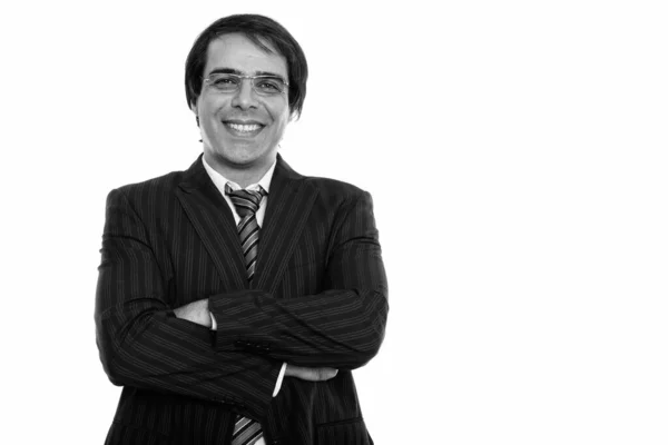 Studio shot de jeune homme d'affaires persan heureux souriant tout en portant des lunettes avec les bras croisés — Photo