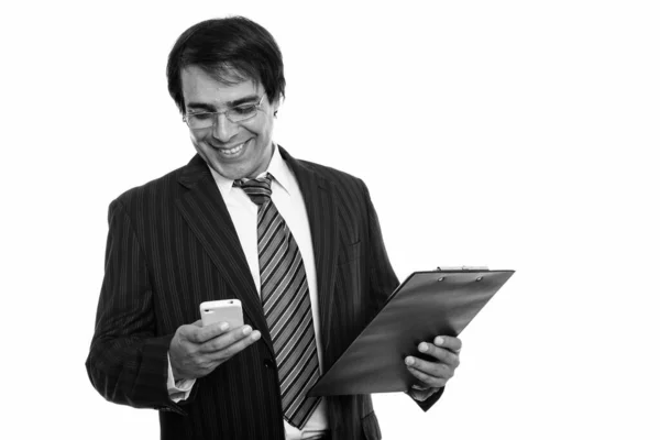 若い幸せなペルシャのビジネスマン笑顔とクリップボードを保持しながら携帯電話を使用して — ストック写真
