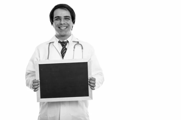 Estudio disparo de joven feliz hombre persa médico sonriendo mientras sostiene pizarra en blanco — Foto de Stock