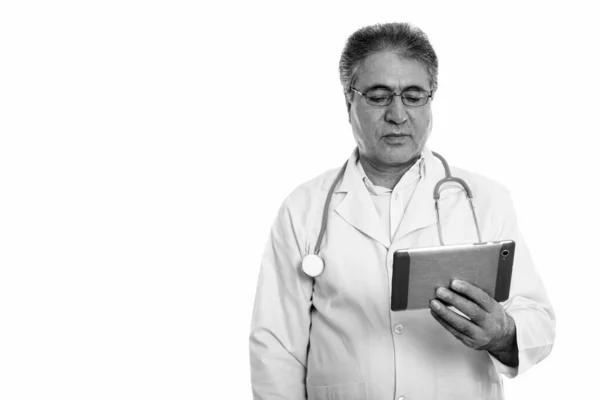 Studio shot of senior Persian man doctor using digital tablet — Stock Photo, Image