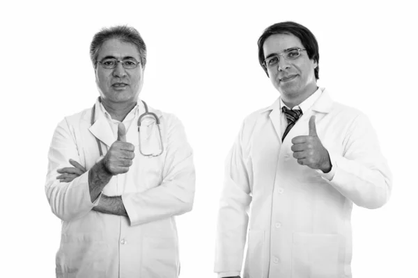 Studio shot of young and senior Persian man doctor giving thumb up — Stock Photo, Image