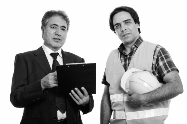 Studio skott av senior persisk affärsman som håller urklipp med ung persisk man byggnadsarbetare — Stockfoto
