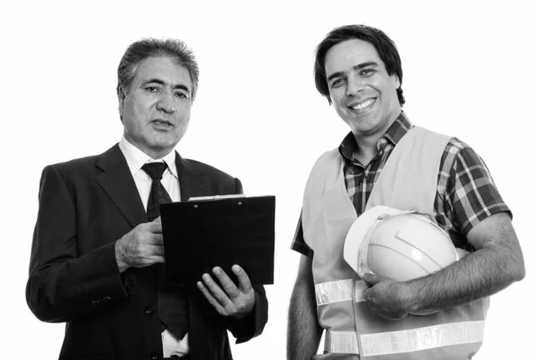 Glad senior persisk affärsman håller urklipp med ung persisk man byggnadsarbetare leende — Stockfoto