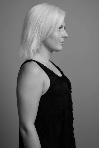 Žena s blond vlasy proti šedému pozadí — Stock fotografie