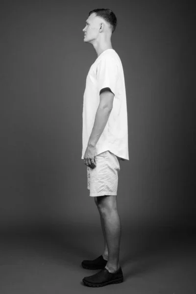 Young man wearing white shirt against gray background — Stock Photo, Image