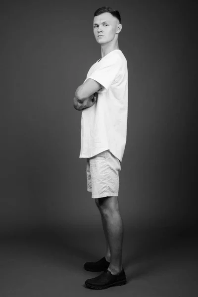 Jovem vestindo camisa branca contra fundo cinza — Fotografia de Stock
