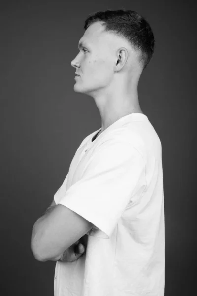 Young man wearing white shirt against gray background — Stock Photo, Image