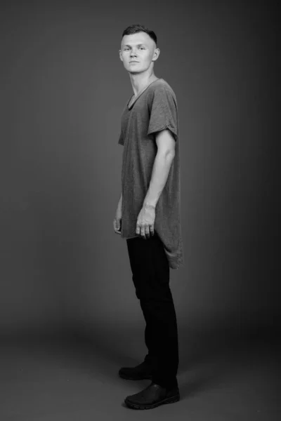 Young man wearing gray shirt against gray background — Stock Photo, Image