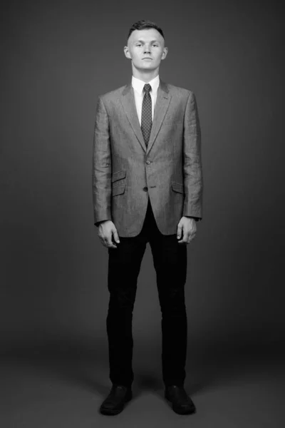 Νεαρός επιχειρηματίας με κοστούμι σε γκρι φόντο — Φωτογραφία Αρχείου