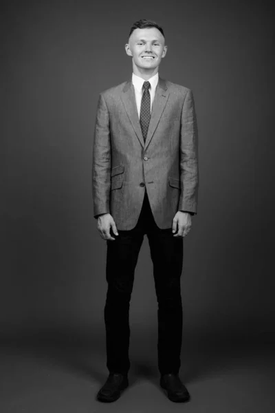 Молодий бізнесмен в костюмі на сірому фоні — стокове фото
