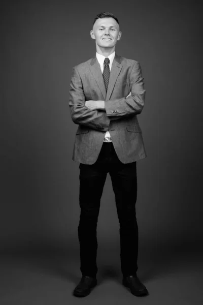 Young businessman wearing suit against gray background — Stock Photo, Image