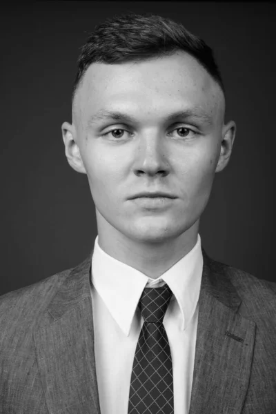 Young businessman wearing suit against gray background — Stock Photo, Image