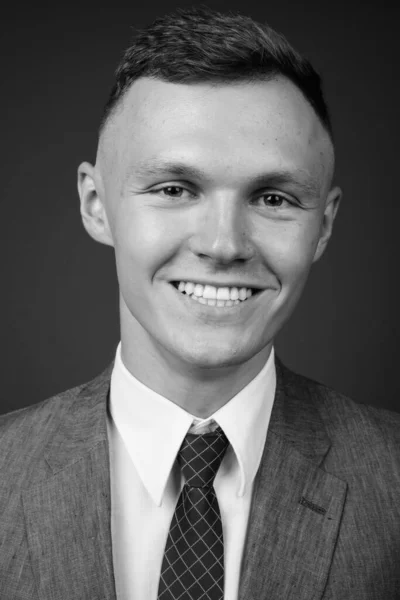 Young businessman wearing suit against gray background — Stock Photo, Image