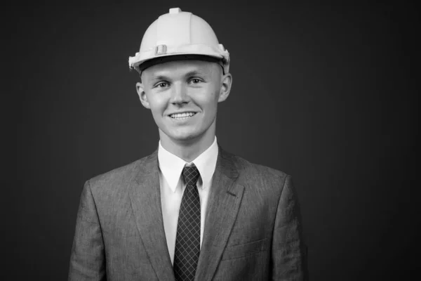 Joven hombre de negocios con sombrero de fuerza sobre fondo gris — Foto de Stock