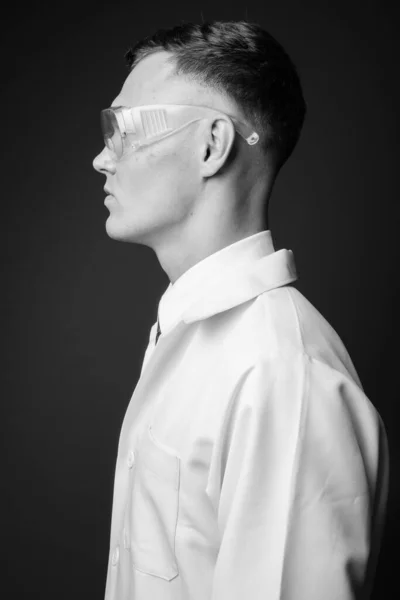 Joven doctor con gafas protectoras sobre fondo gris —  Fotos de Stock