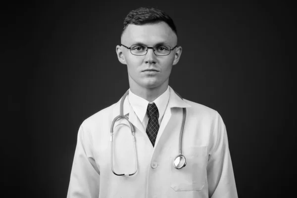 Νεαρός γιατρός φοράει γυαλιά με γκρι φόντο — Φωτογραφία Αρχείου