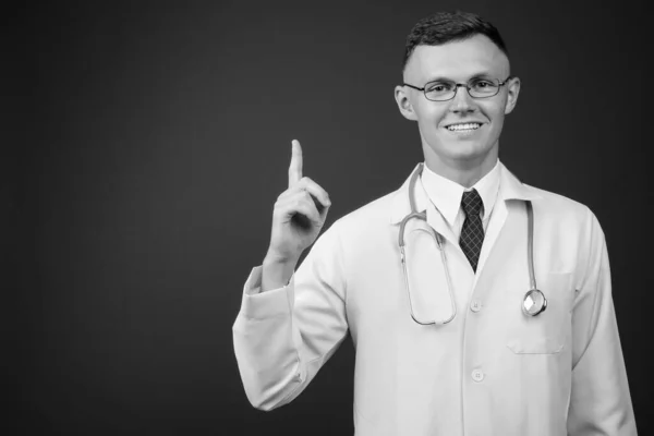 Молодий чоловік лікар в окулярах на сірому фоні — стокове фото
