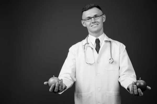 Молодий чоловік лікар в окулярах на сірому фоні — стокове фото