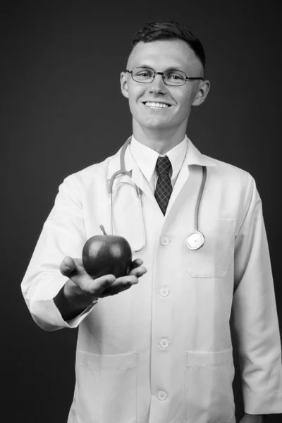 Jovem médico vestindo óculos contra fundo cinza — Fotografia de Stock
