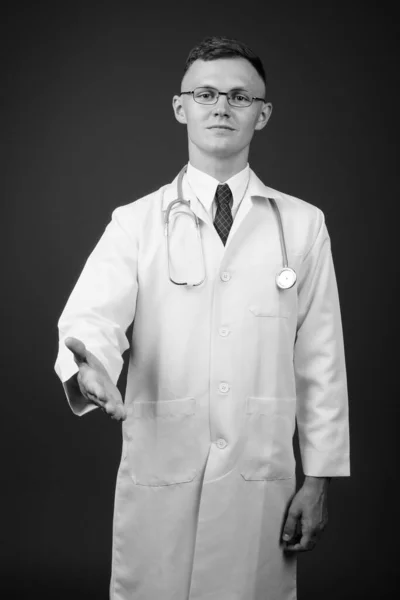 Joven doctor vistiendo anteojos sobre fondo gris — Foto de Stock