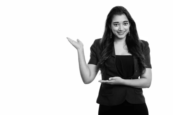 Studio shot di giovane donna d'affari indiana felice sorridente mentre mostra qualcosa — Foto Stock