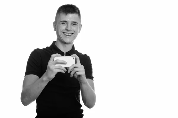 年轻快乐的白人男人微笑着，拿着手机拍照，看着相机 — 图库照片