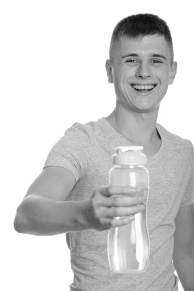 Jovem homem caucasiano feliz sorrindo e dando garrafa de água — Fotografia de Stock