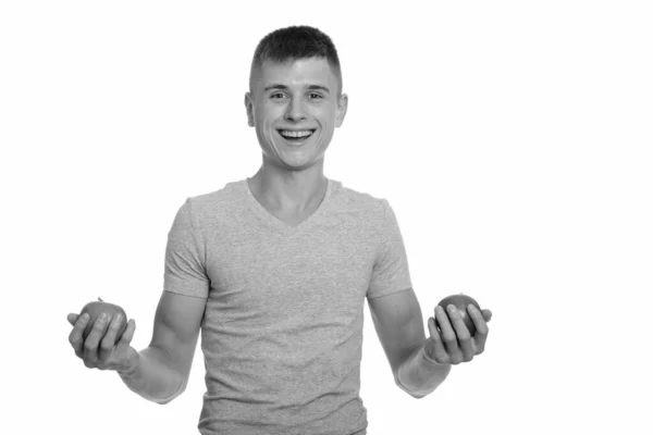 Junger glücklicher Kaukasier lächelt, während er zwei Äpfel in der Hand hält — Stockfoto