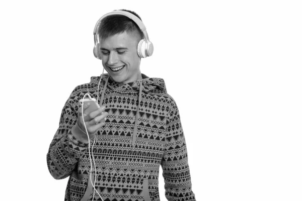 Young happy Caucasian man smiling while using mobile phone and listening to music — Stock Photo, Image