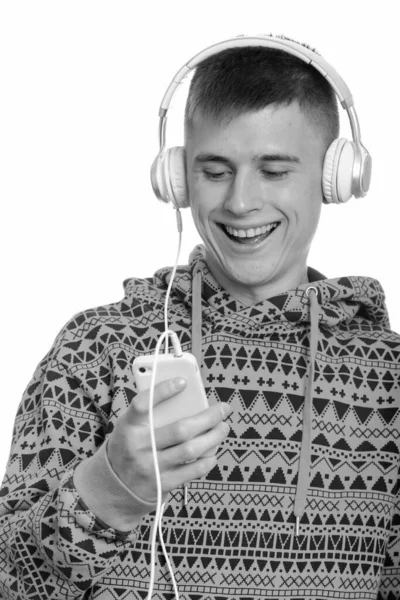 Primer plano de joven feliz hombre caucásico sonriendo mientras se utiliza el teléfono móvil y escuchar música —  Fotos de Stock