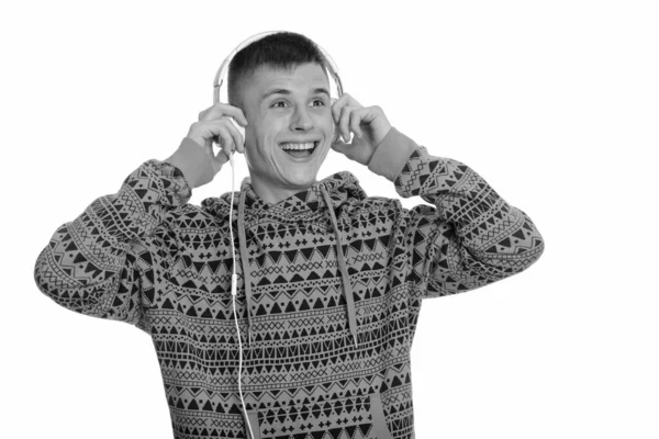 Молодой счастливый кавказский мужчина улыбается и слушает музыку, думая: — стоковое фото
