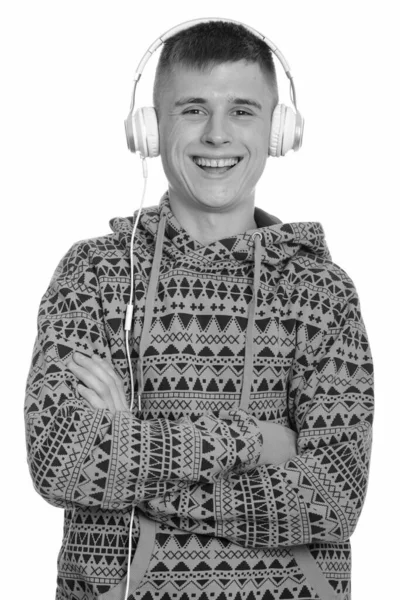 Молодий кавказький чоловік усміхається, слухаючи музику зі схрещеними руками. — стокове фото