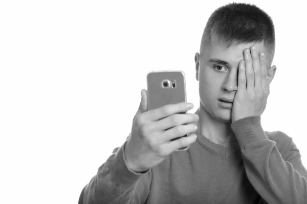 Joven hombre caucásico sosteniendo teléfono móvil mirando estresado —  Fotos de Stock