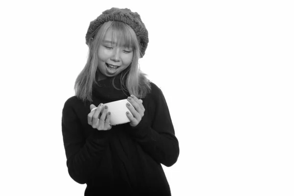 Jovem mulher asiática feliz sorrindo enquanto segurando e olhando para xícara de café — Fotografia de Stock