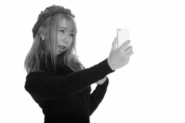 Молодая счастливая азиатка улыбается и делает селфи с мобильного телефона — стоковое фото