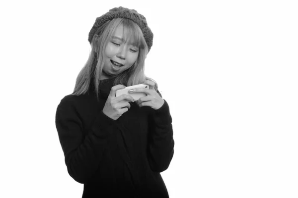 Молода азіатка посміхається і користується мобільним телефоном. — стокове фото