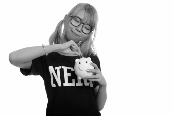 Junge süße asiatische Nerd-Frau steckt Münze in Sparschwein — Stockfoto