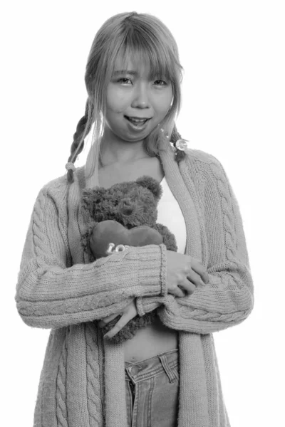 Young happy Asian woman smiling and hugging teddy bear with heart and love sign — Stock Photo, Image