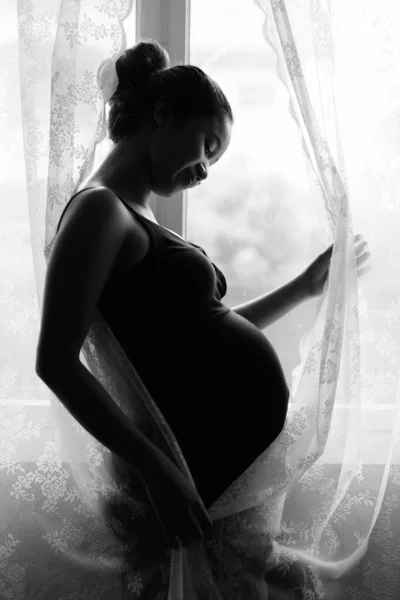 Madre amando il suo bambino in silhouette dalla finestra — Foto Stock