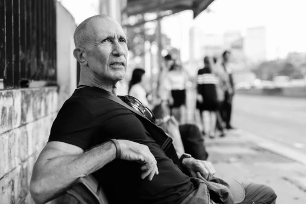 Bald senior turist man väntar och sitter på träbänk vid busshållplatsen i Bangkok Thailand — Stockfoto