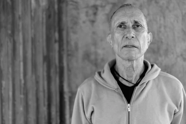 Close-up van kale senior man dragen hoodie tegen oude betonnen muur — Stockfoto
