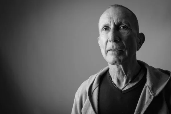 Närbild av skallig senior man tänker medan du bär huvtröja mot grå bakgrund — Stockfoto