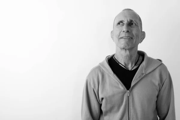 Studio shot of happy bald senior man souriant et pensant sur fond blanc — Photo