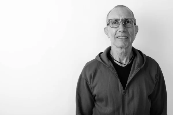 Plan studio d'un homme âgé chauve heureux souriant tout en portant des lunettes sur fond blanc — Photo