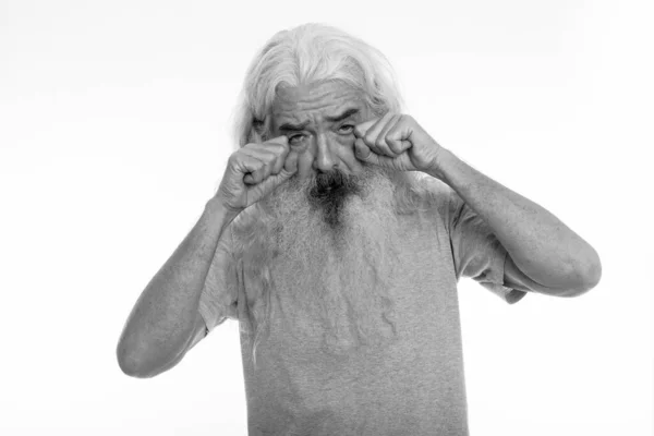 Studio colpo di anziano uomo barbuto guardando triste mentre piange con entrambe le mani sugli occhi — Foto Stock
